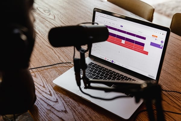micro de podcast devant un PC ouvert sur un bureau