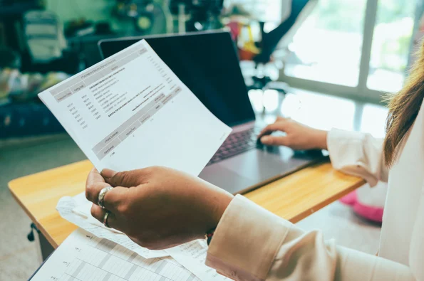 person holding an invoice in one hand and typing with the other